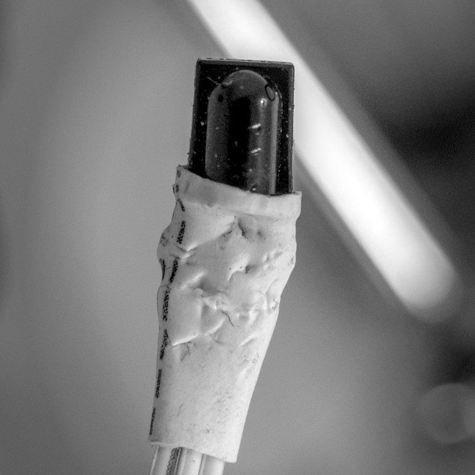 The IR sensor, connected to the cable and the electrical
               connection covered in plastic for electrical protection. The
               thermoplastic has many bite marks.